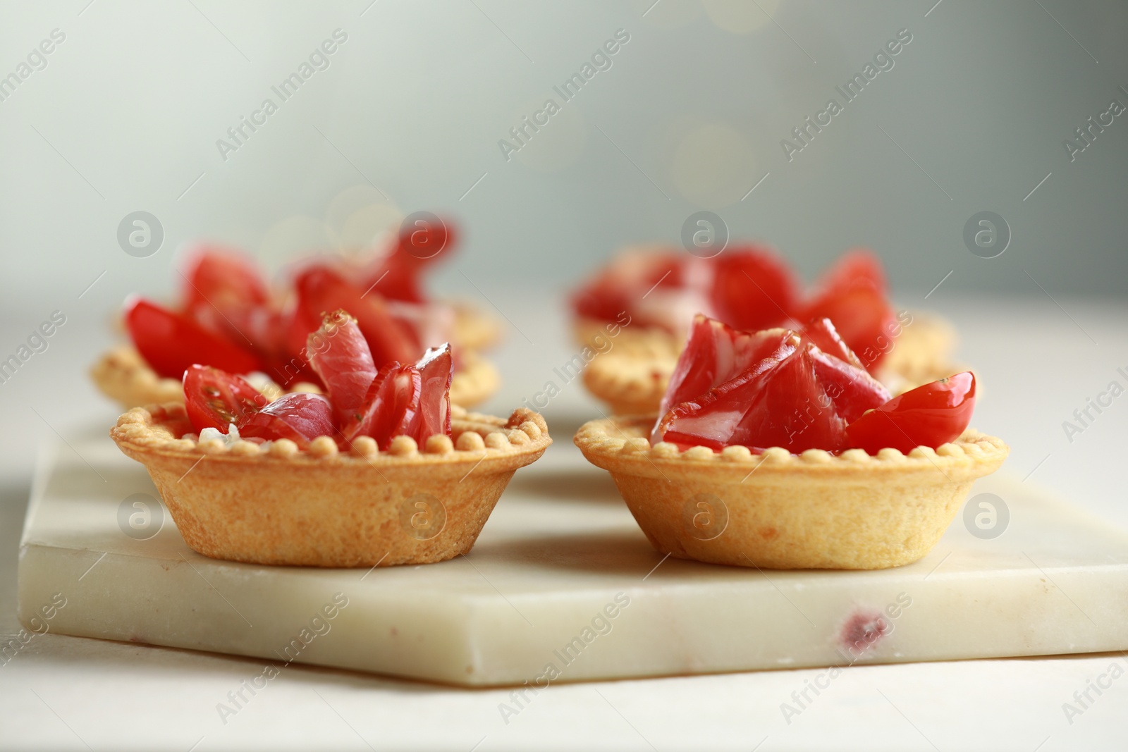 Photo of Delicious canapes with jamon on white table, closeup