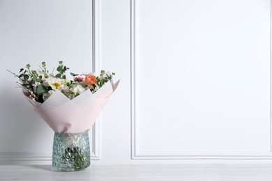 Photo of Bouquet of beautiful flowers in vase on wooden table against white wall. Space for text