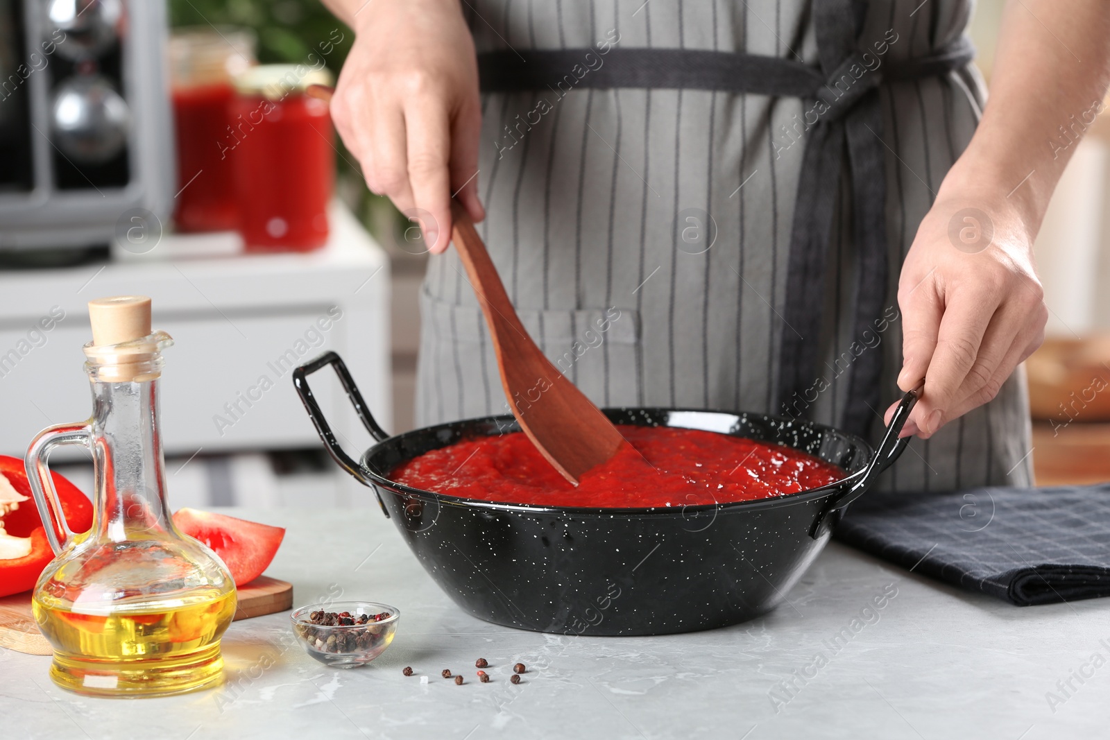 Photo of Woman cooking delicious tomato sauce in pan at table, closeup