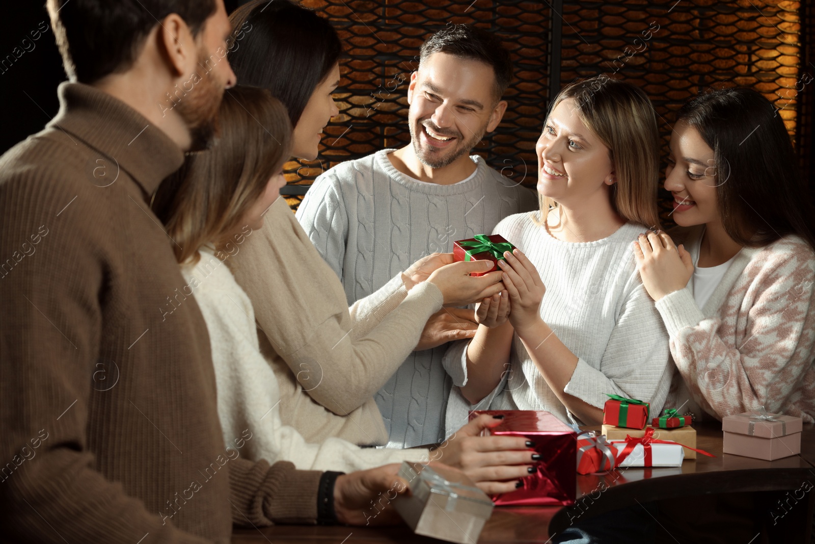 Photo of Friends exchanging gifts at table in cafe