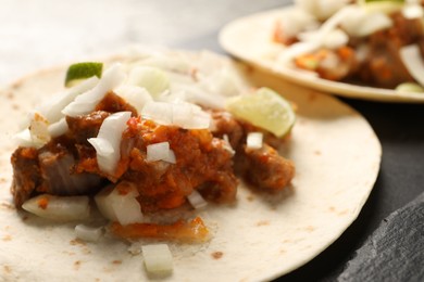 Photo of Delicious tacos with vegetables, meat and lime on dark table, closeup