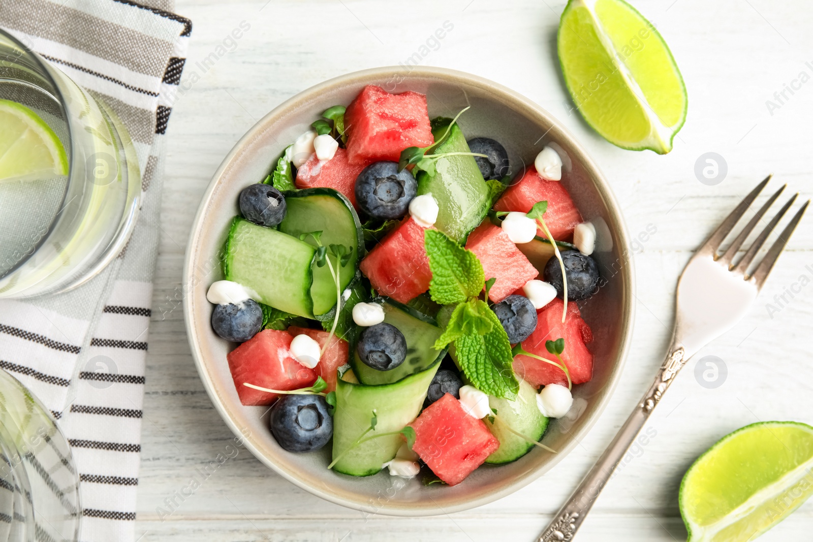 Photo of Delicious salad with watermelon served on white wooden table, flat lay