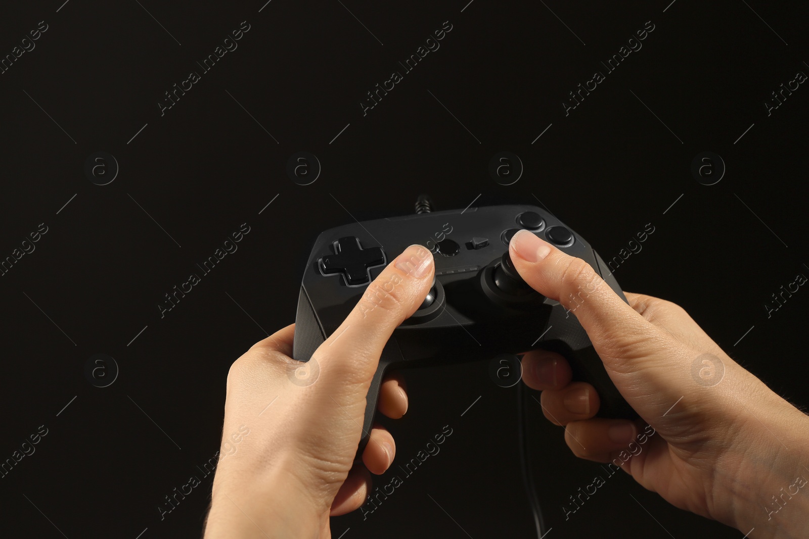 Photo of Woman holding video game controller on black background, closeup