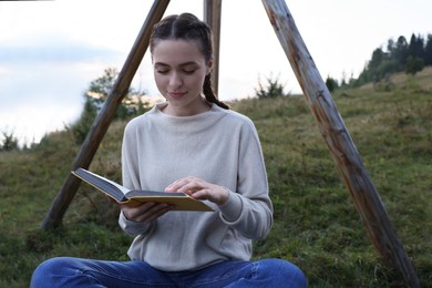 Photo of Beautiful young woman reading book in evening outdoors