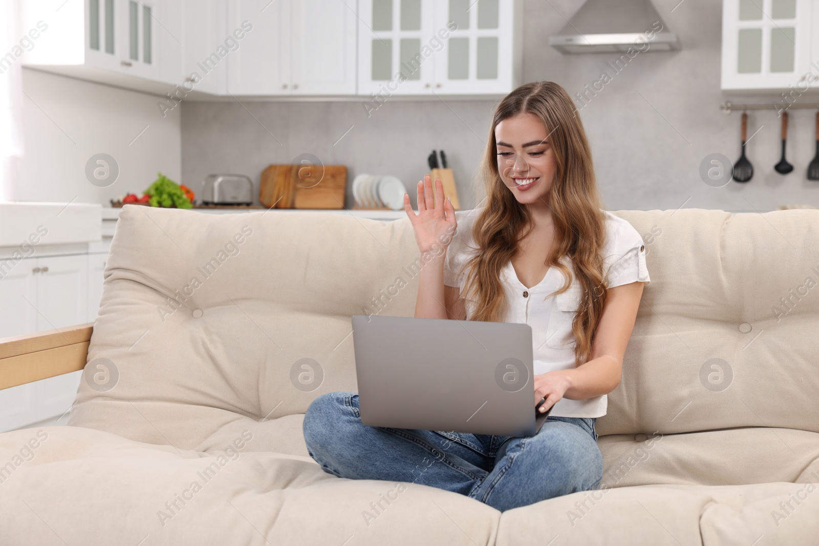 Photo of Happy woman having video chat via laptop on couch in room