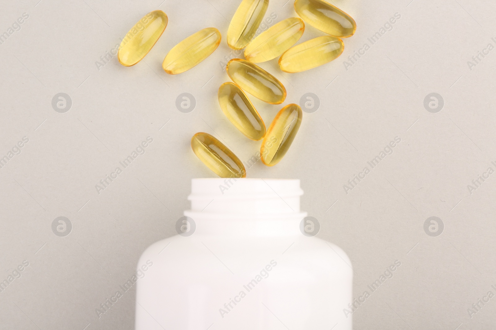 Photo of Bottle and vitamin capsules on light grey background, top view