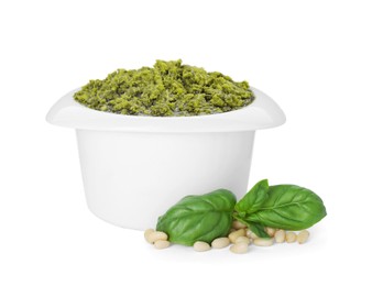 Photo of Delicious pesto sauce in bowl, basil and pine nuts isolated on white