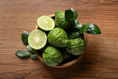 Photo of Fresh ripe bergamot fruits with green leaves on wooden table, top view