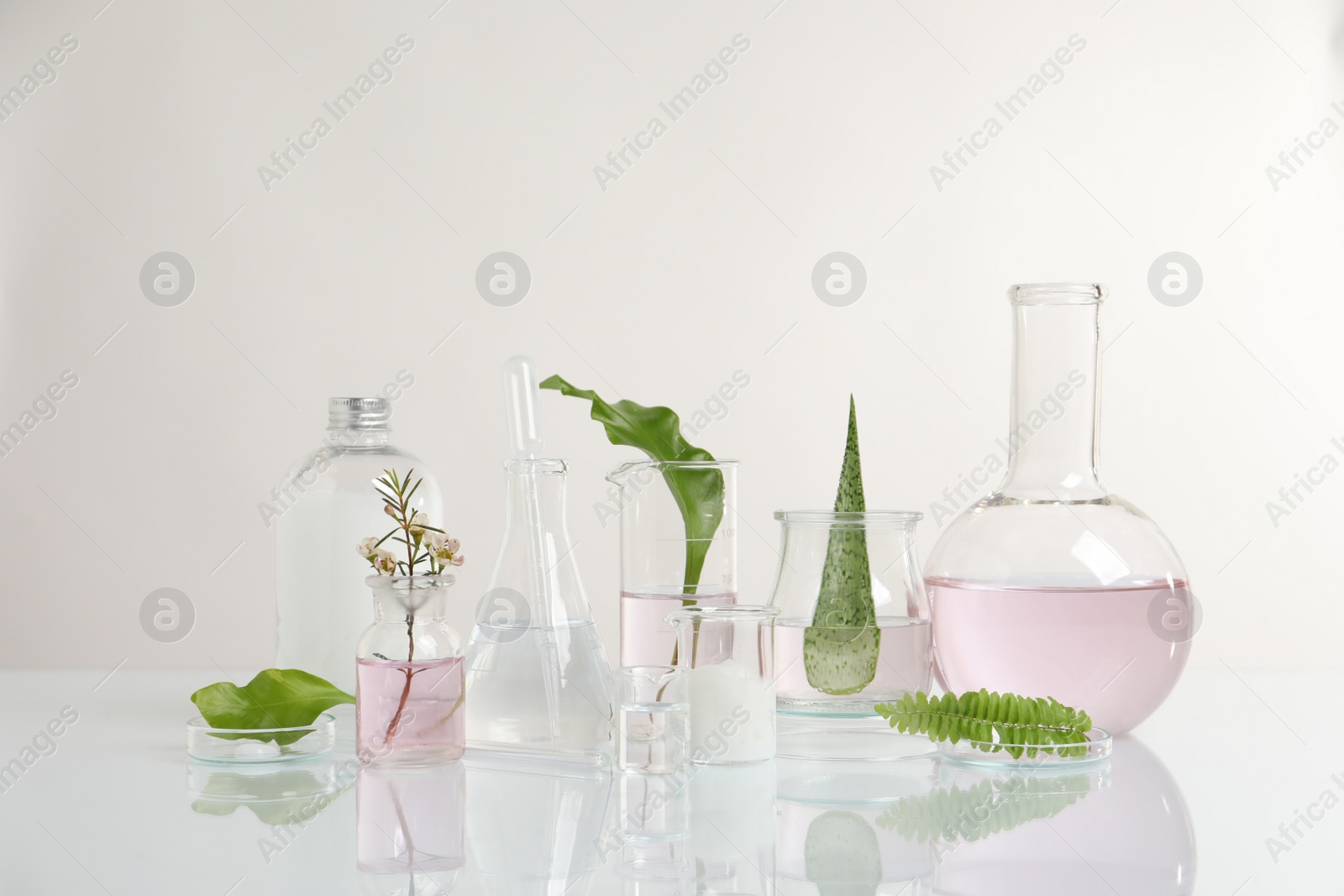 Photo of Natural ingredients and laboratory glassware for organic cosmetic product on white table