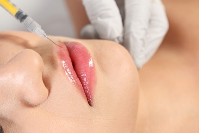 Photo of Young woman getting lips injection, closeup. Cosmetic surgery