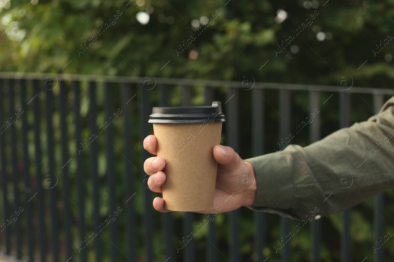 Photo of Coffee to go. Man with paper cup of drink outdoors, closeup