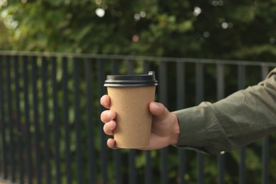 Coffee to go. Man with paper cup of drink outdoors, closeup