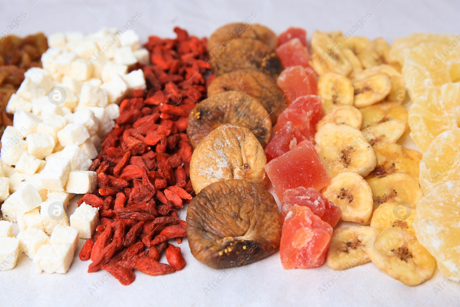 Photo of Different tasty dried fruits on paper, closeup