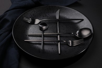 Photo of Stylish table setting. Plate, napkin and cutlery on black background