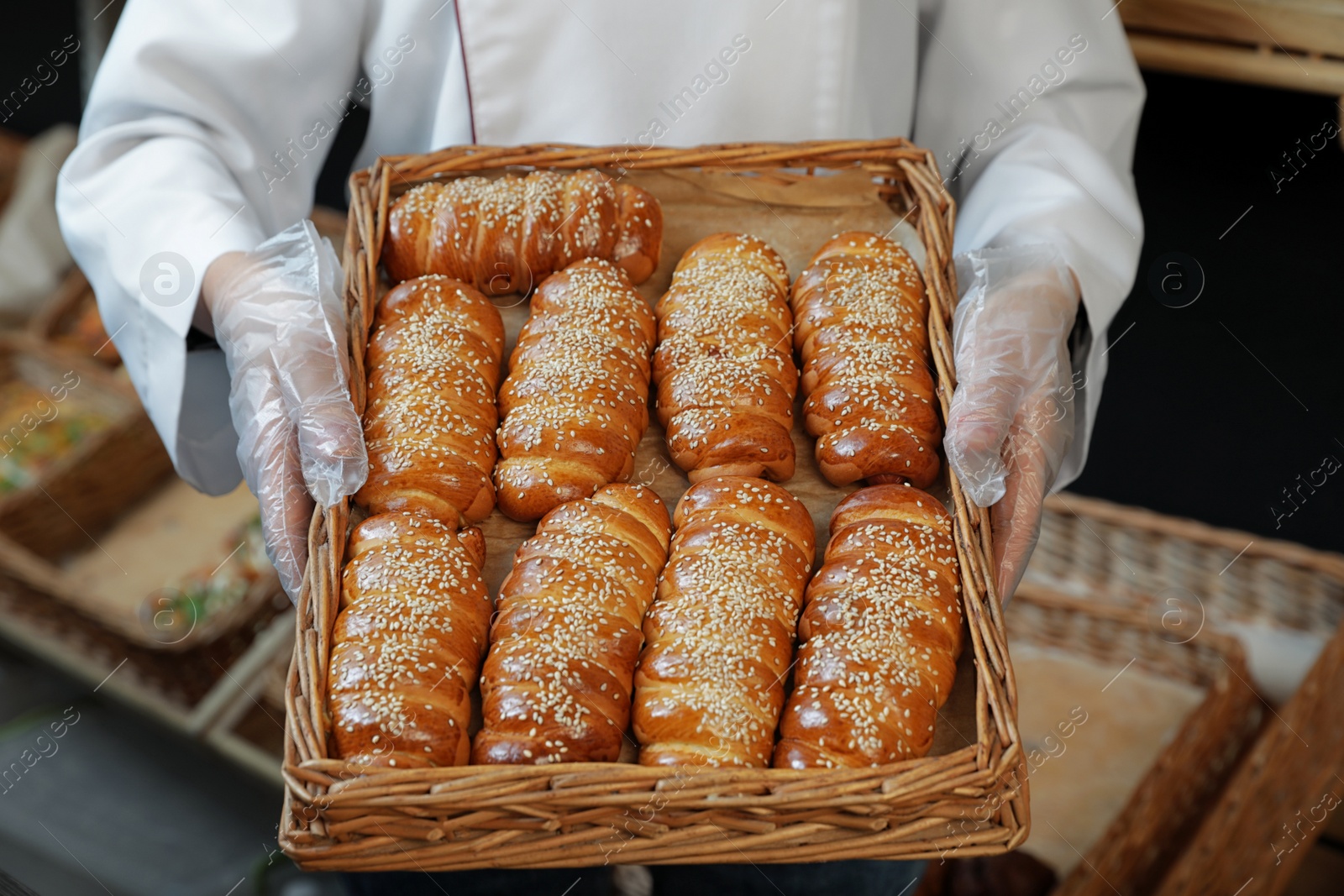 Photo of Baker holding tray with fresh buns in store, closeup