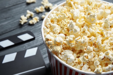 Photo of Fresh tasty popcorn in bucket on wooden background, closeup with space for text. Cinema snack