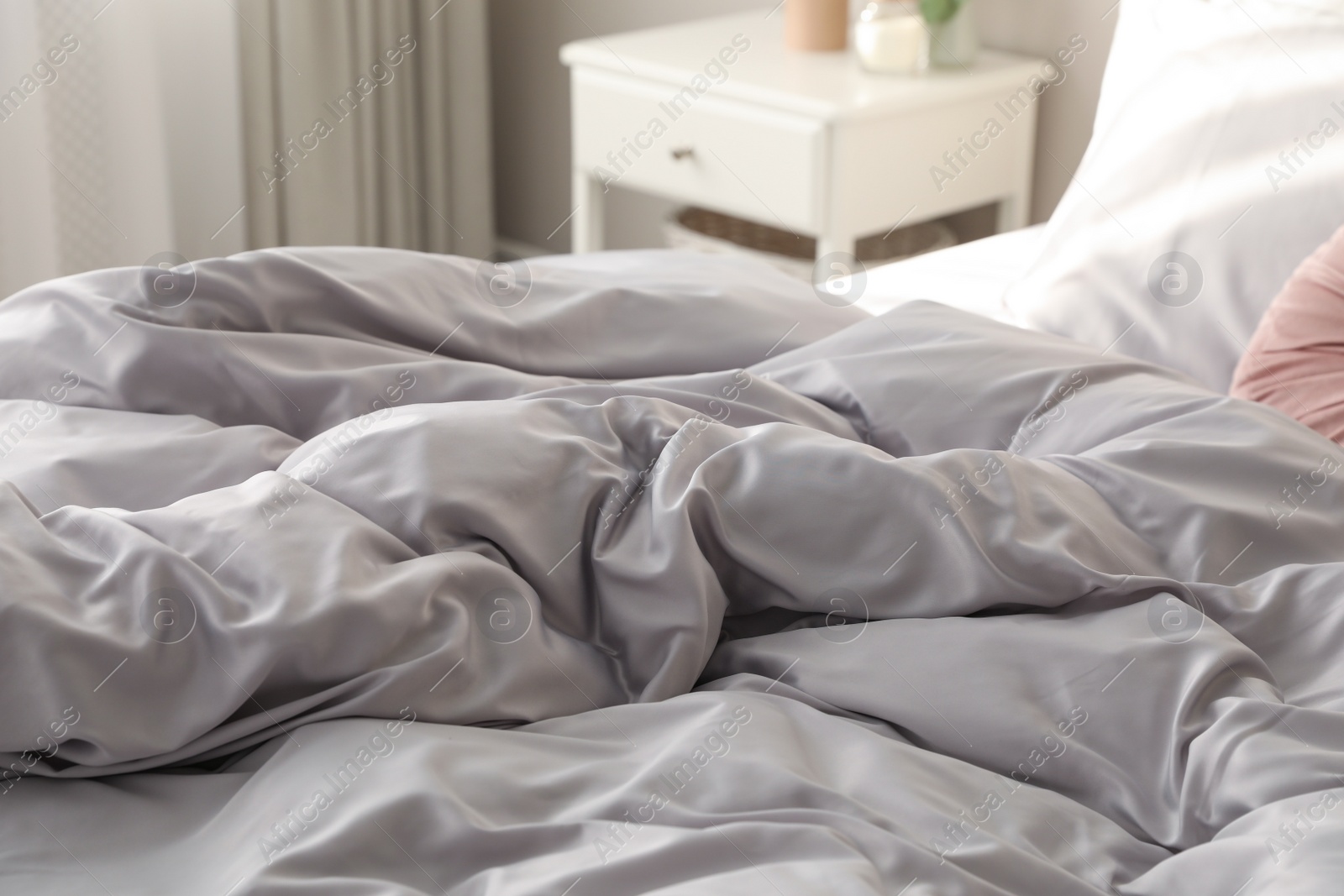 Photo of Bed with stylish silky linens in room