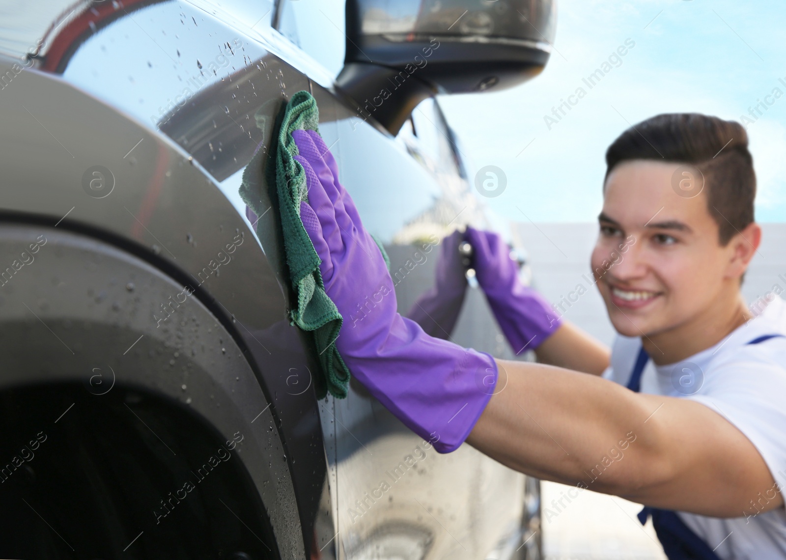 Photo of Male worker cleaning automobile with rag at car wash