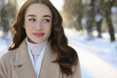 Portrait of beautiful woman in snowy park. Space for text