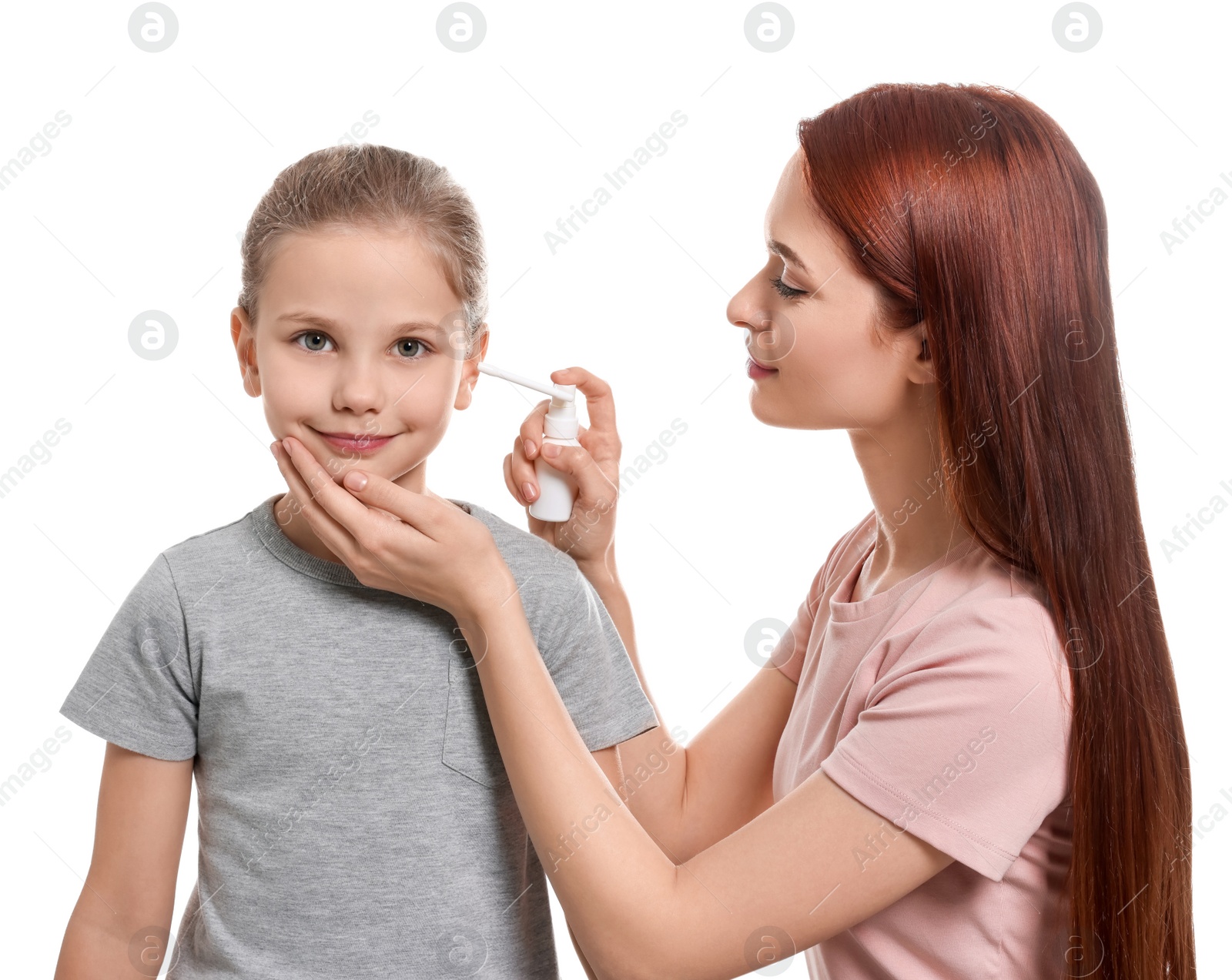 Photo of Mother spraying medication into daughter's ear on white background