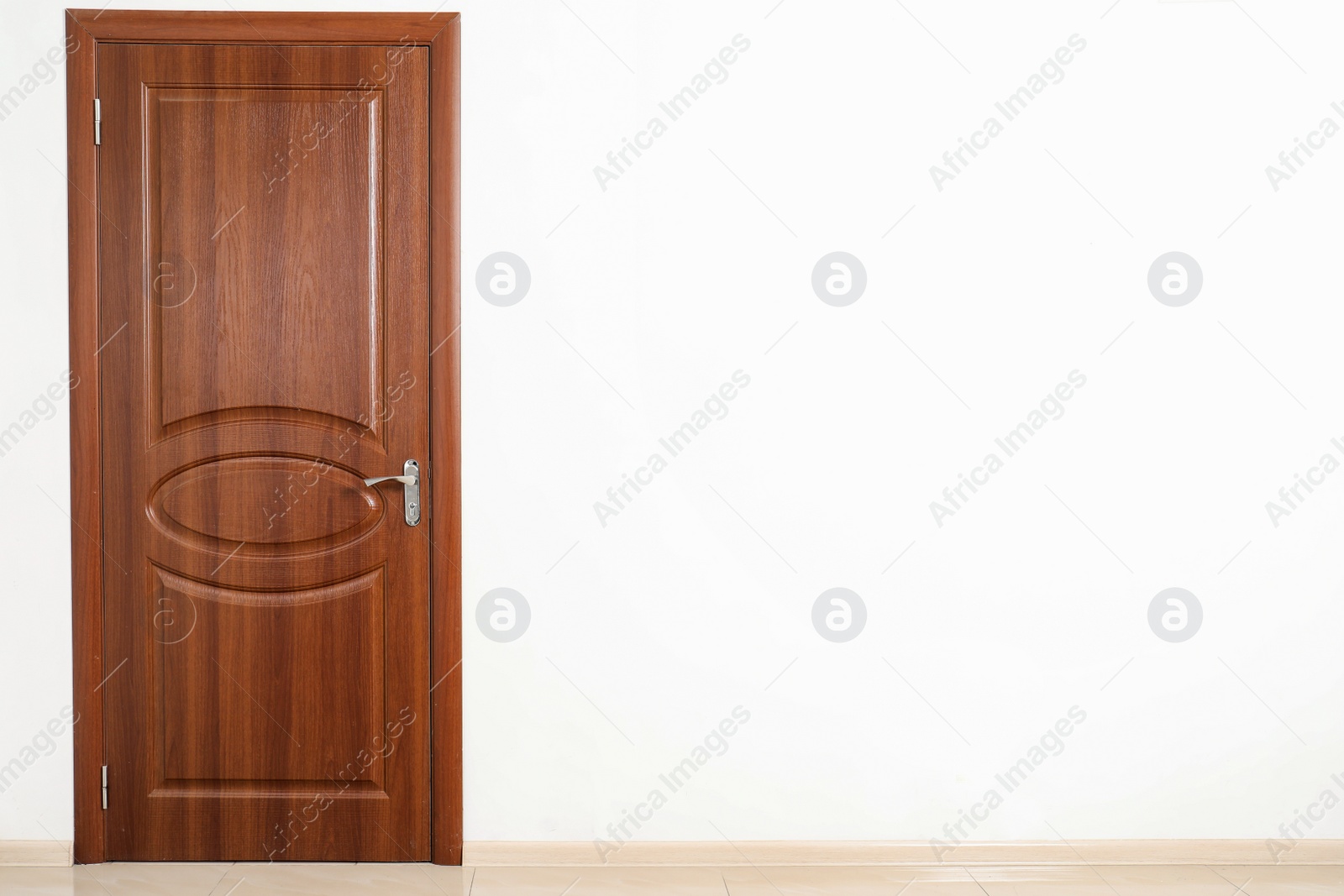 Photo of Closed brown door in white wall. Space for text