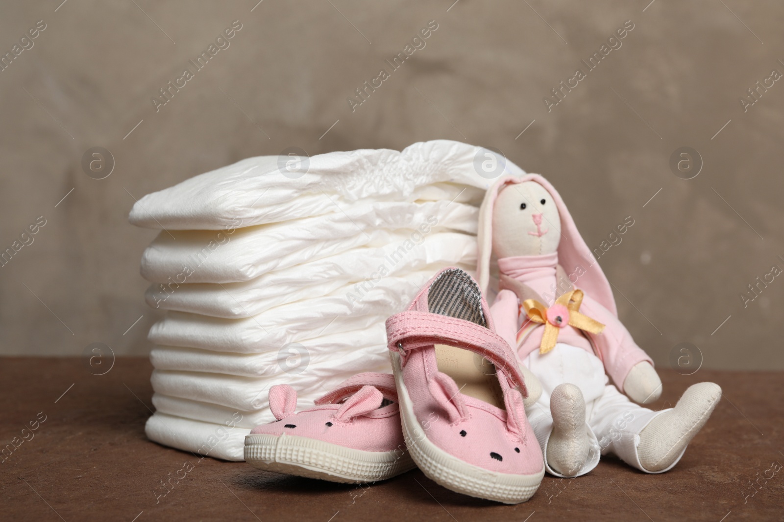 Photo of Baby diapers, toy bunny and child's shoes on wooden table