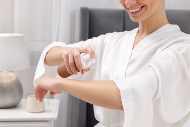 Photo of Woman applying self-tanning product onto arm indoors, closeup