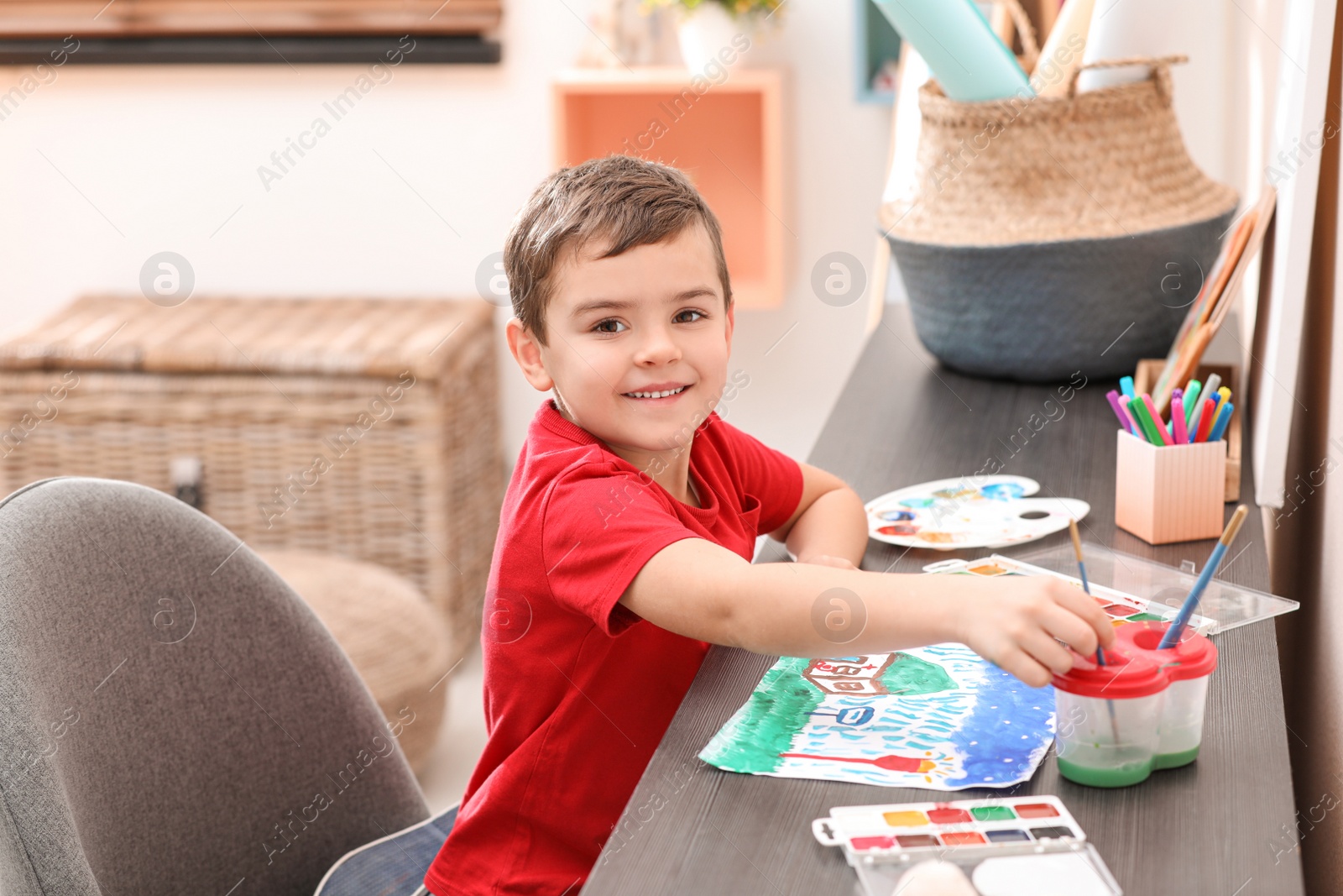 Photo of Little child painting at table in room