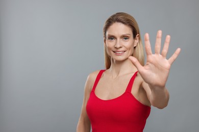 Photo of Woman giving high five on grey background. Space for text