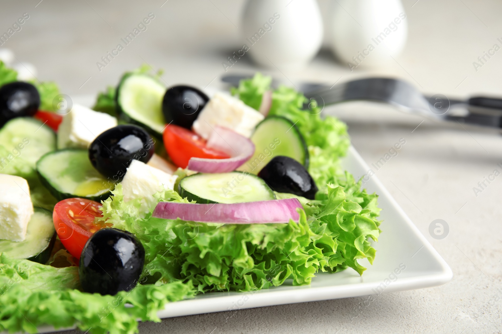 Photo of Tasty fresh Greek salad on grey table, closeup