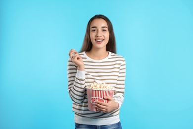 Woman with popcorn during cinema show on color background