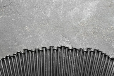 Photo of Pile of metal nails on grey stone background, flat lay. Space for text