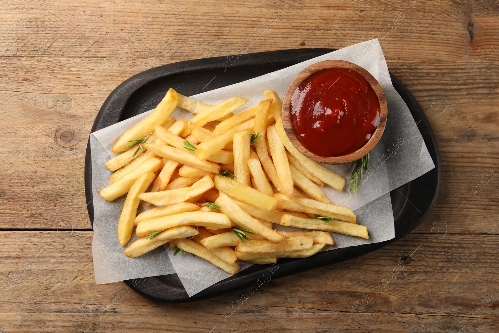 Photo of Delicious french fries served with ketchup on wooden table, top view