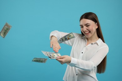 Happy woman throwing money on light blue background