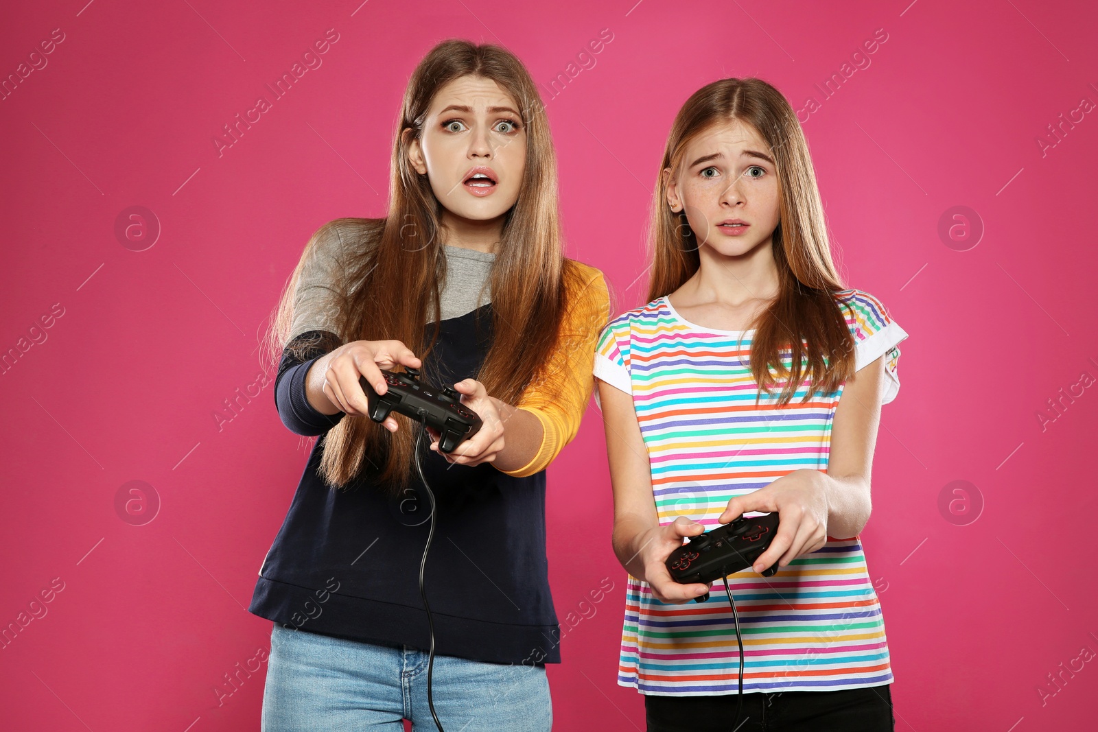 Photo of Young woman and teenage girl playing video games with controllers on color background