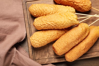 Photo of Delicious deep fried corn dogs on wooden table, top view