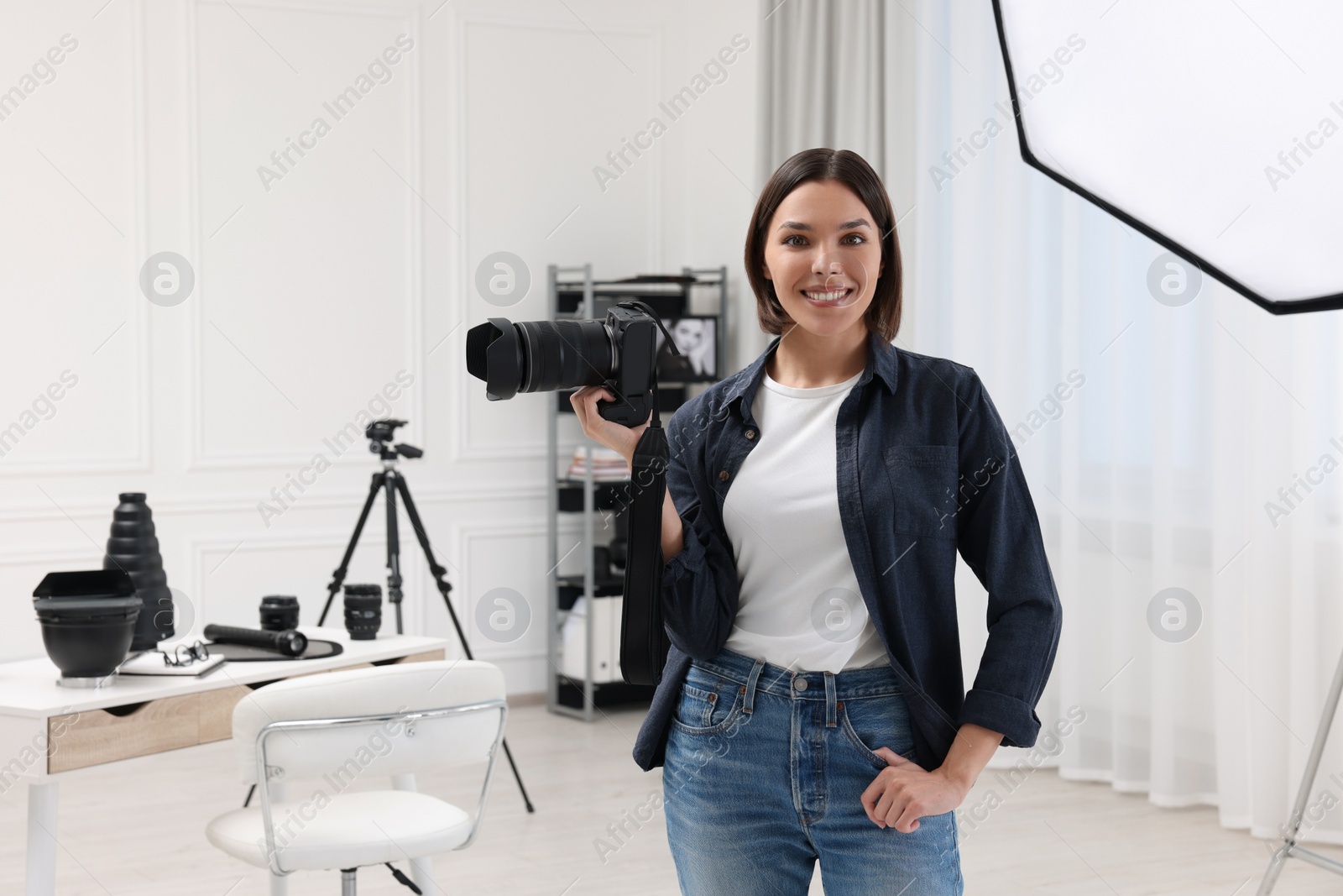 Photo of Young professional photographer with camera in photo studio, space for text