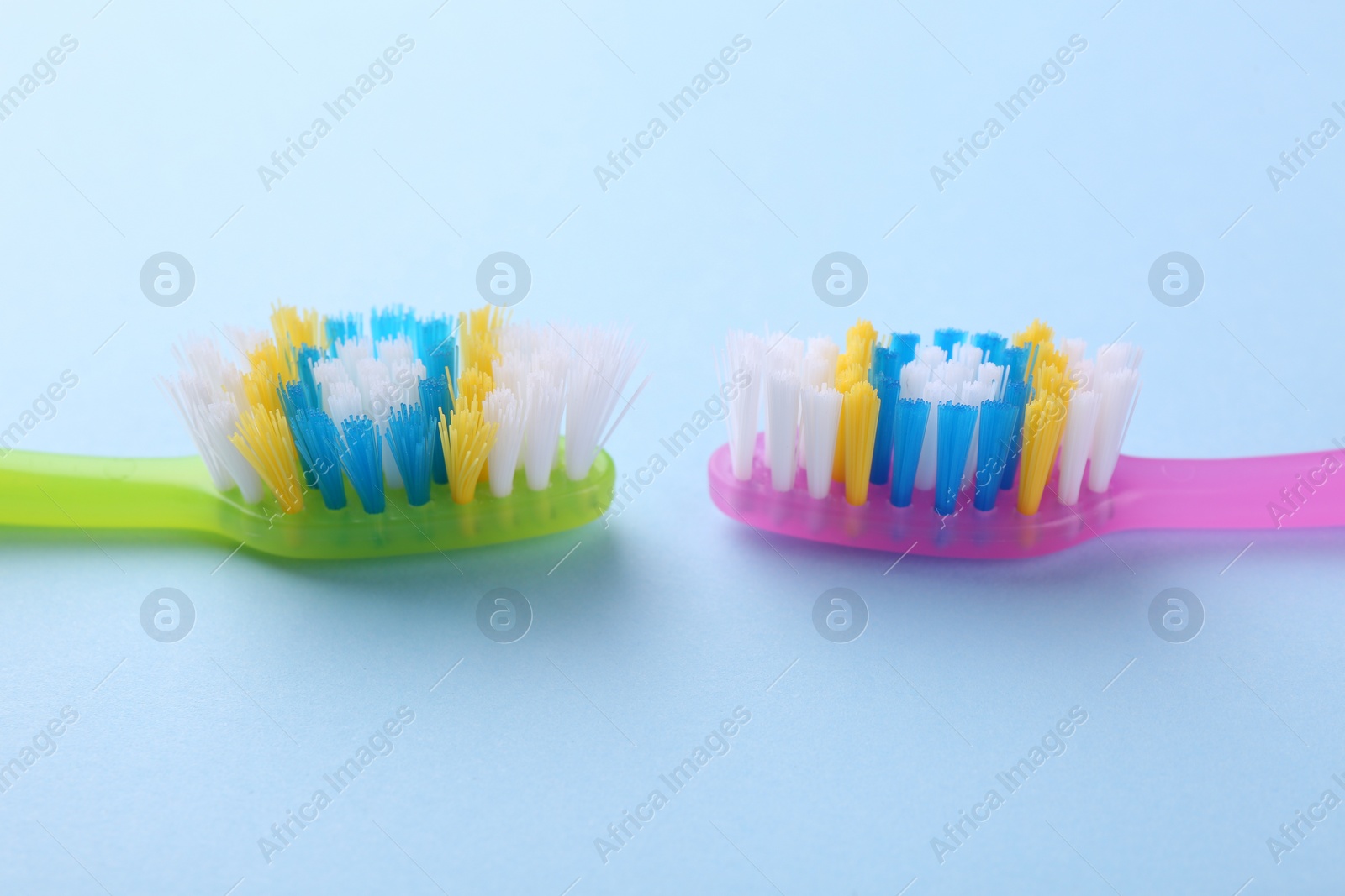 Photo of Colorful plastic toothbrushes on light blue background, closeup