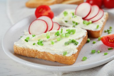 Photo of Toasted bread with cream cheese and vegetables on white table, closeup