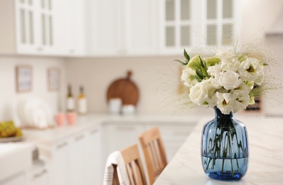 Bouquet of beautiful eustoma flowers on white table in kitchen. Interior design