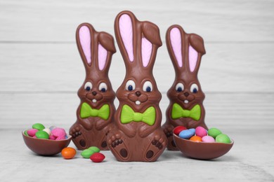 Photo of Easter celebration. Funny chocolate bunnies and sweets on white textured background