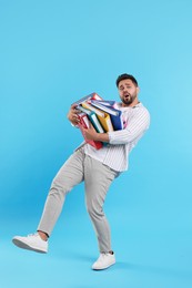 Photo of Frustrated man with folders walking on light blue background