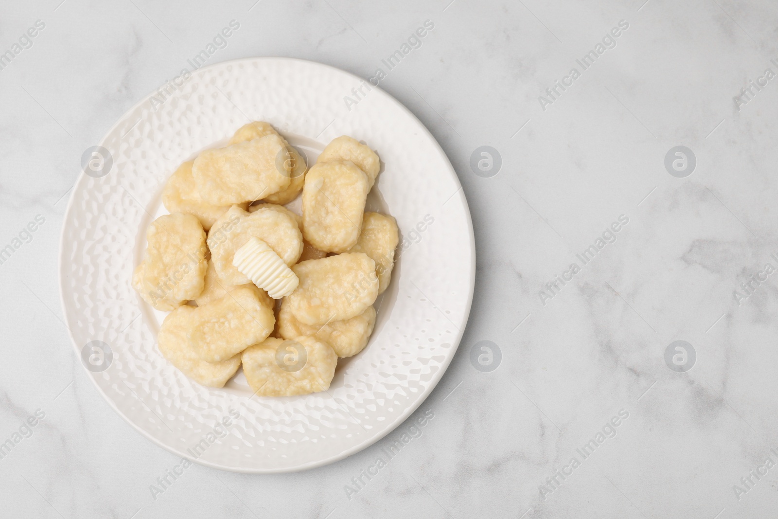 Photo of Plate of tasty lazy dumplings with butter on white marble table, top view. Space for text