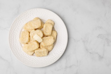 Photo of Plate of tasty lazy dumplings with butter on white marble table, top view. Space for text