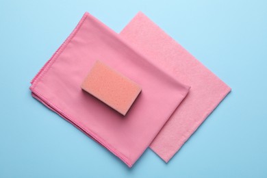 Photo of Sponge and rags on light blue background, top view
