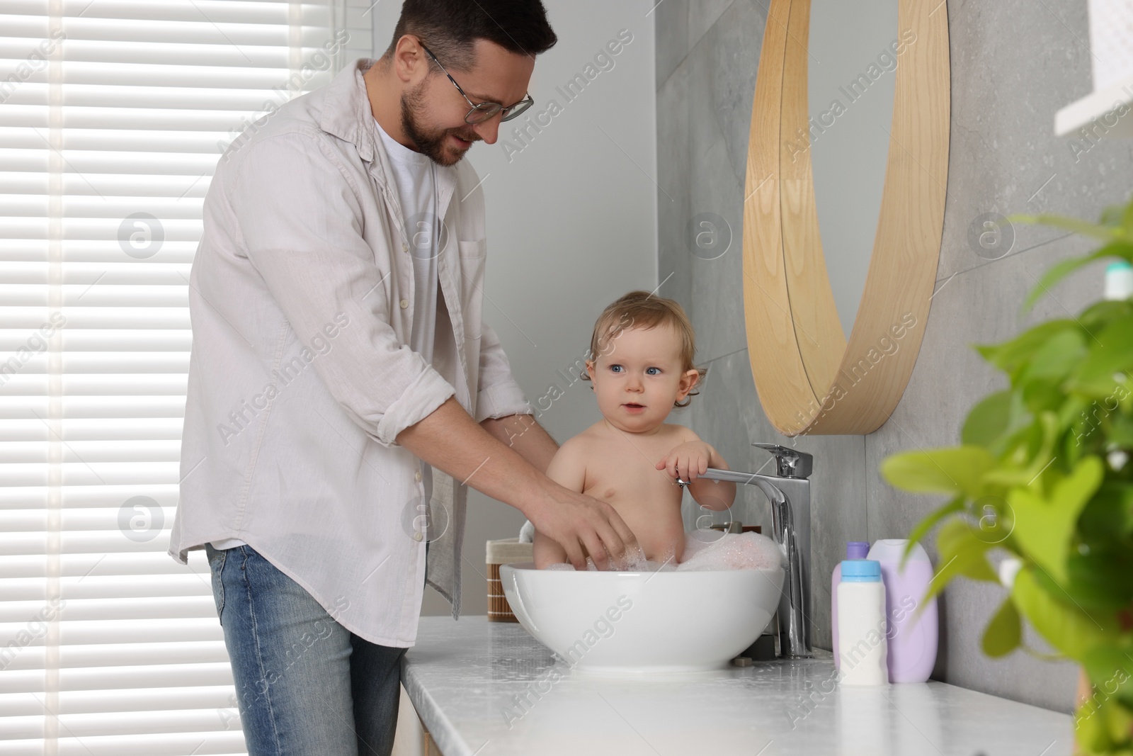 Photo of Father washing his little baby in sink at home