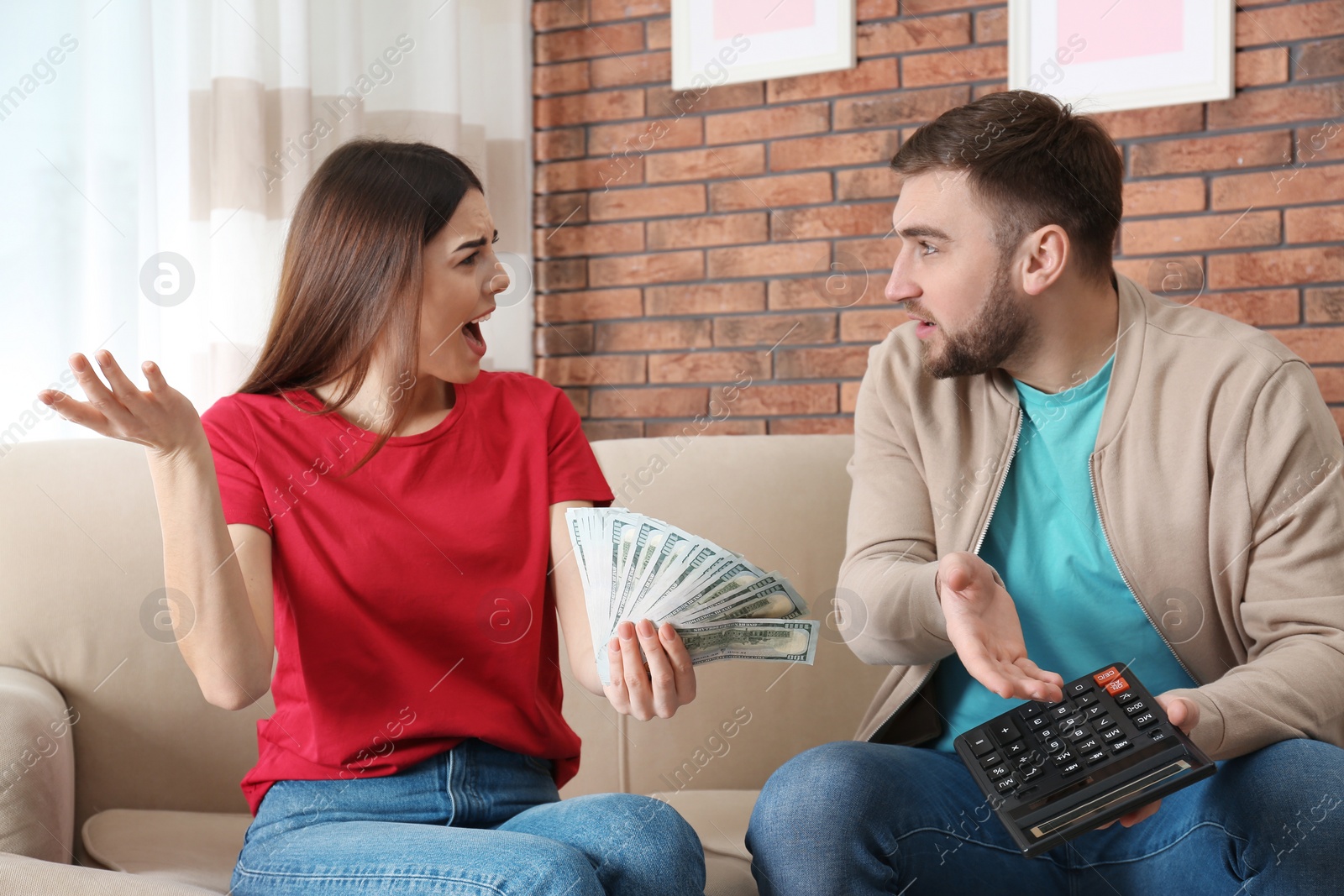 Photo of Unhappy young couple with money at home. Financial problems