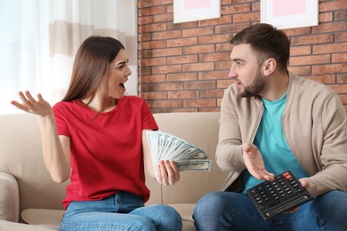 Photo of Unhappy young couple with money at home. Financial problems