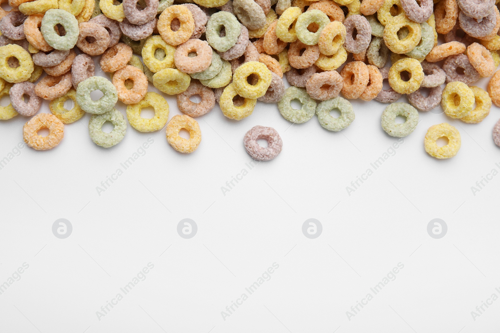 Photo of Tasty cereal rings on white background, flat lay. Space for text