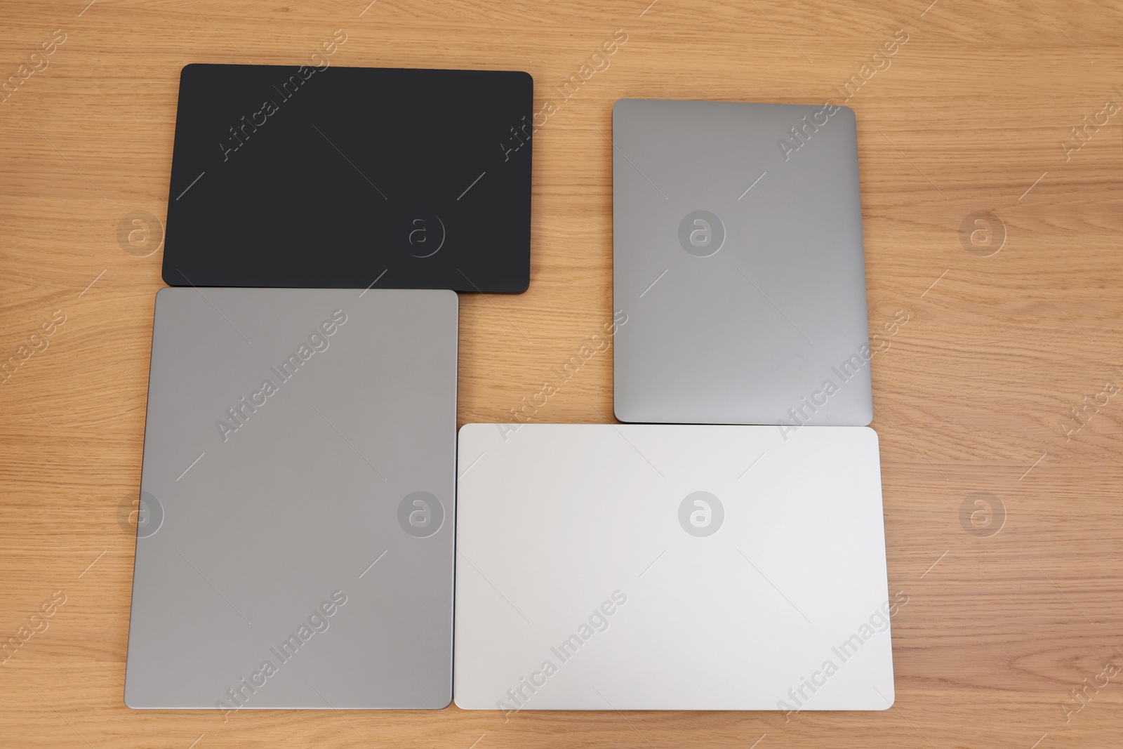 Photo of Different modern laptops on wooden table, above view